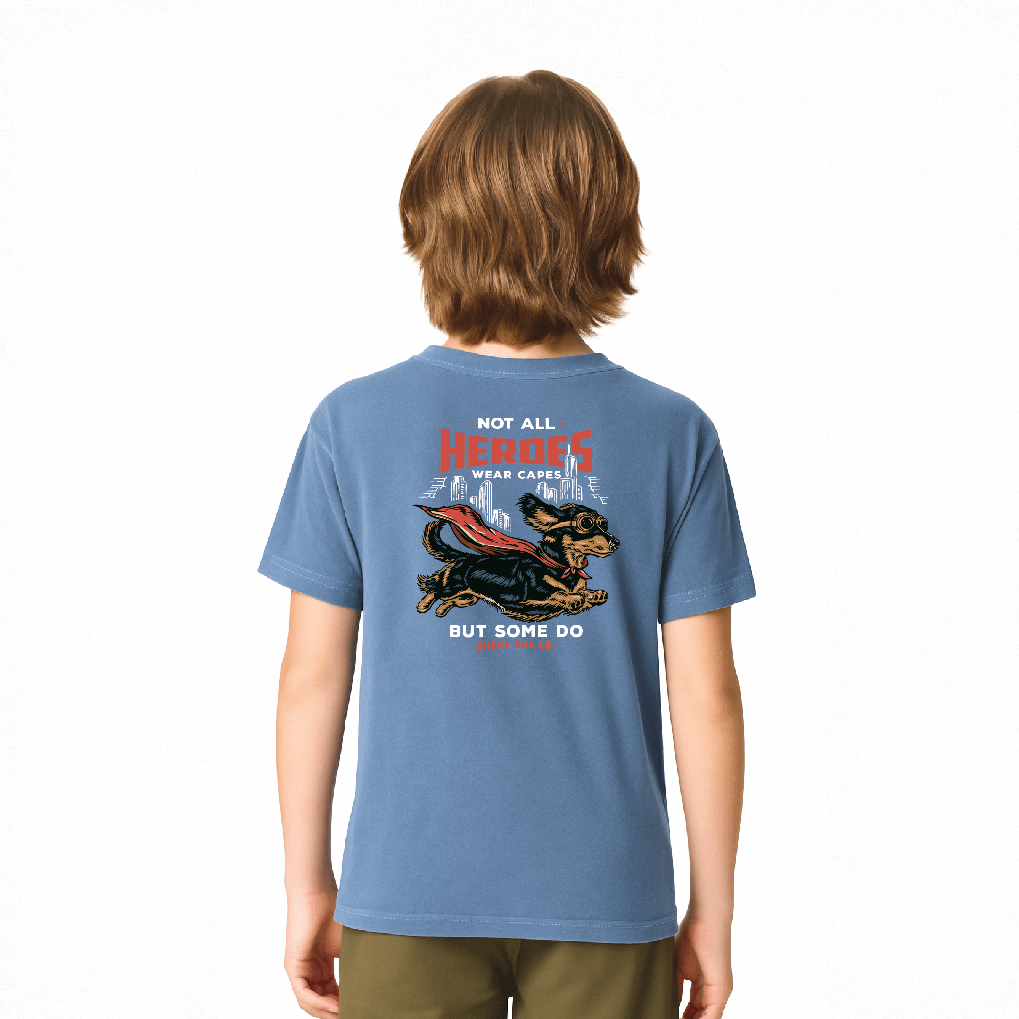 Child wearing a blue washed denim tee featuring a dog in a cape with the text 'Not All Heroes Wear Capes'.